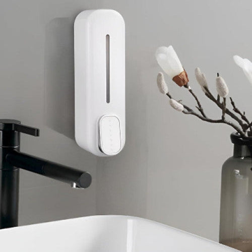White soap dispenser mounted on a gray wall above a sink with decorative elements.